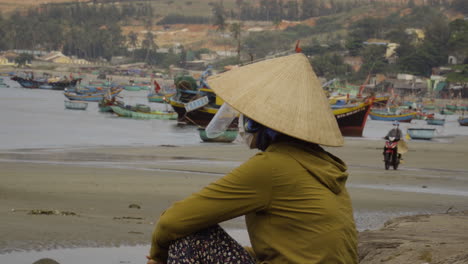 Asian-woman-wear-conical-straw-hat-with-face-shield-and-mask-sit-on-beach-alone