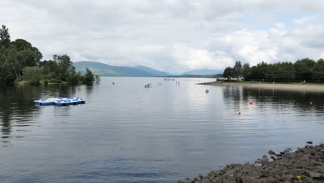 Landscape-with-people-rowing-on-paddleboards-on-the-Loch-Lomond-in-Scotland,-active-lifestyle-and-water-sport