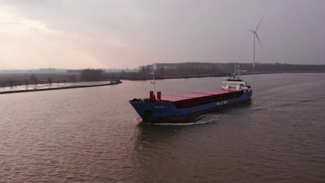 Aerial-Port-Side-View-Of-Wilson-Leith-Cargo-Ship-On-Oude-Maas-With-Wind-Turbines-In-Background