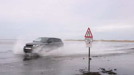 Expensive-luxury-cars-driving-through-salt-water-on-a-beach-road