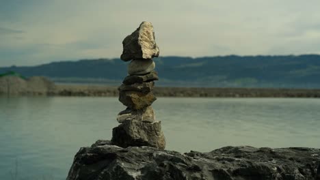 Balancing-stone-with-lake-and-mountain-in-the-background