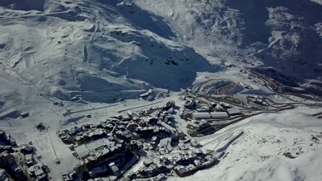 View-of-Val-Thorens-frozen-grounds-surrounded-by-snow-capped-mountain-Range---Aerial-pan-tilt-up-shot