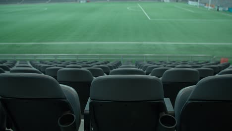 Empty-seats-of-football-stadium-with-green-grass-in-background