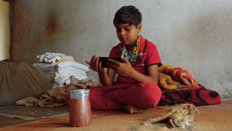 Young-Indian-Boy-Sits-on-Floor-Intently-Watching-Streaming-Video-on-Smartphone