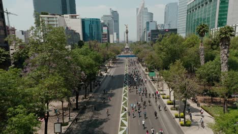 Aerial-wide-angle-drone-above-cyclists-at-road-near-monument-to-independence