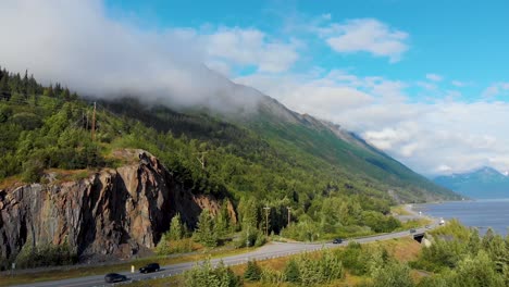 4K-Drone-Video-of-Cars-Travelling-on-Seward-Highway-at-Base-of-Mountain-Along-Shoreline-of-Turnagain-Inlet-Near-Anchorage-During-Summer