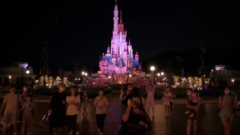 Visitors-take-photos-and-walk-through-the-park-before-the-American-amusement-park-Disneyland-Resort-closes-as-the-iconic-Disney's-Castle-is-seen-in-the-background-in-Hong-Kong