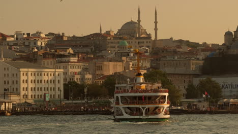Wunderschöne-Goldene-Stunde,-Teleaufnahme-Der-Fähre,-Die-In-Eminönü,-Istanbul-Ankommt,-Mit-Der-Nuruosmaniye-Moschee-Im-Hintergrund