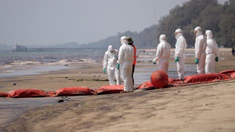 Workers-In-White-PPE-Suit-Conducting-Clean-up-Operations-Due-To-Oil-Spill-At-Mae-Ram-Phueng-Beach-In-Rayong,-Thailand