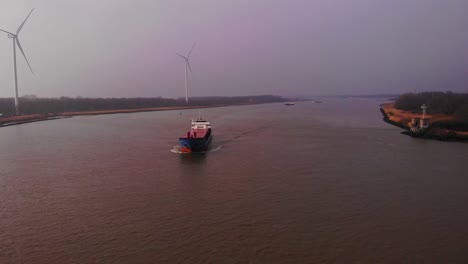 Aerial-Of-Wilson-Leith-Cargo-Ship-On-Oude-Maas-With-Wind-Turbines-In-Background-On-Cloudy-Day