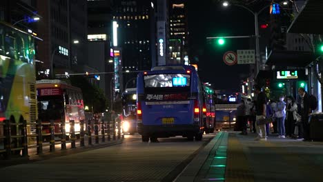 Seúl,-Corea-Del-Sur-15-De-Septiembre-De-2021,---Personas-Con-Máscaras-Esperando-Un-Autobús-Cuando-Muchos-Autobuses-Públicos-De-La-Ciudad-Pasan-Conduciendo-En-Carriles-De-Autobuses-En-El-Centro-De-Seúl,-Plataforma-De-La-Parada-De-Autobús-De-La-Estación-De-Gangnam-Por-La-Noche