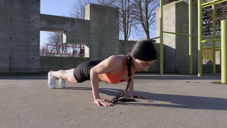 Young-lean-woman-doing-pushups-outdoors-Slider-shot-track-left