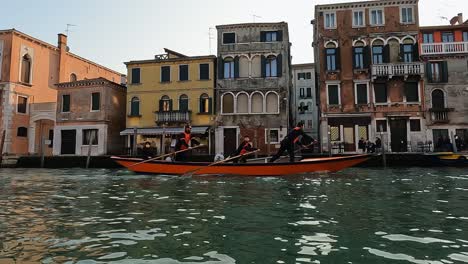 Team-of-four-rowers-training-rowing-standing-on-Venetian-canal-of-Venice-in-Italy