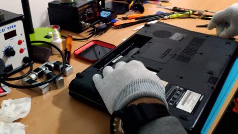 Gloved-Male-Hands-Placing-SSD-Back-In-Laptop-And-Screwing-Back-Cover
