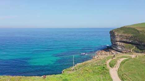 Tourists-walking-in-border-of-green-blue-turquoise-seaside-cliff