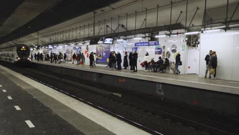 Metro-entering-metro-station-Charles-de-Gaulle---Étoille-in-Paris,-France,-while-commuters-wait-on-the-platform