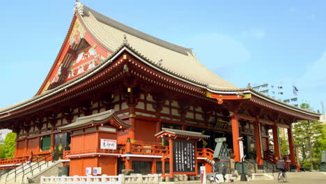 ASAKUSA,-TOKYO,-JAPAN,-circa-April-2020:-people-walking-in-authentic-Japanese-temple-with-gorgeous-craftmanship-decoration-on-roof-and-wall-on-sunny-spring-day