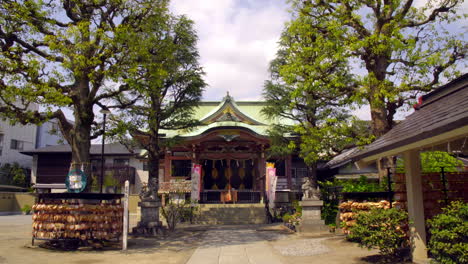 ASAKUSA,-TOKYO,-JAPAN-circa-April-2020:-man-worshipping-at-authentic-Japanese-temple,-gorgeous-architecture-with-beautiful-roof,-in-peaceful-and-quiet-zen-style-garden-on-a-sunny-spring-day