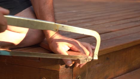 Carpenter's-Hand-Cutting-Wood-With-Metal-Saw