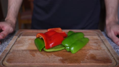 Close-up-of-person-showing-peppers-cut-into-pieces-on-a-wooden-board