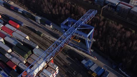 Shipping-container-crane-lift-unloading-heavy-cargo-export-crate-containers-in-shipyard-aerial-view-top-down-reversing-shot