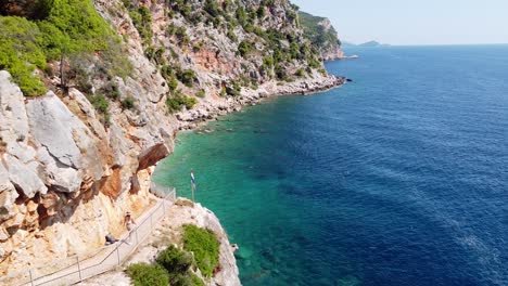 Tourist-Girl-Walks-to-Hidden-Pasjaca-Beach-in-Dalmatia,-Croatia---Aerial-Dolly
