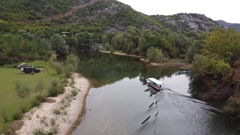 Tourist-tuoBoat-Sails-over-Crnojevica-River-to-Lake-Skadar,-Montenegro---Aerial-Dolly