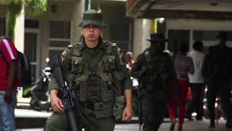 A-young-Colombian-military-man-holding-a-rifle-keeping-a-lookout-among-civilians-in-a-busy-street