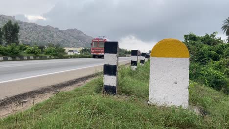 Captured-Real-Photo-of-Plain-Yellow-and-White-Milestone-with-National-Highway-Road-and-green-plants-background