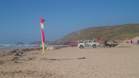 Perranporth-Beach-Sands-Lifeguard-on-Duty-Sitting-on-Truck-Surveys-Surf-With-Rescue-Boat,-Cornwall,-England---Static