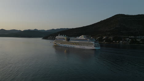 Aerial-5K-Drone-Of-AIDNova-Cruise-Ship-Sailing-Away-From-Scenic-Dubrovnik,-Croatia-At-Sunset