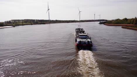Aerial-Dolly-View-Along-Stern-Of-Da-Vinci-Motor-Tanker-Ship-Navigating-Along-Oude-Maas-With-Row-Of-Wind-Turbines-Seen-In-Background