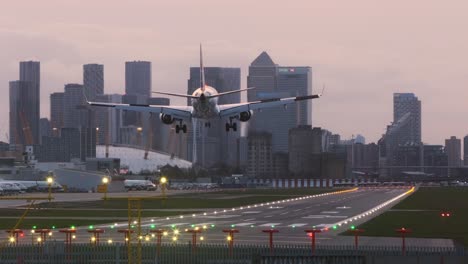 Kleine-Flugzeuge-Landen-Am-London-City-Airport,-Am-Abend-Canary-Wharf-Im-Hintergrund