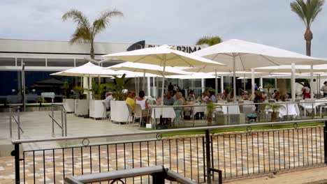 People-eating-outside-of'-'Punta-Prima'-restaurant-in-Spain-on-a-fine-spring-day