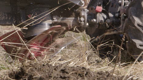 Blades-of-a-rototiller-working-on-topsoil,-agriculture,-slow-motion-close-up