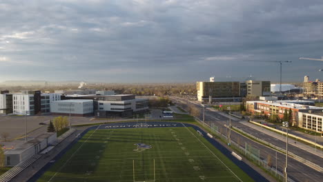 aerial-view-of-urban-football-field,-terrain,-playground,-university,-college,-cityscape,-city,-green-grass,-empty-streets,-lockdown,-shutdown,-field,-stadium,-sports