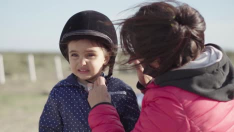 Mom-fix-her-daughter's-helmet-for-the-horseback-ride
