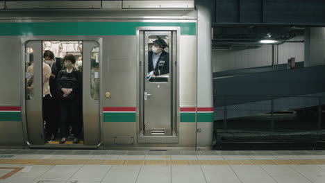 Passagiere-Und-Zugbegleiter-Tragen-Masken-In-Einem-Zug-Am-Bahnhof-Mit-Geschlossener-Tür-In-Sendai,-Japan