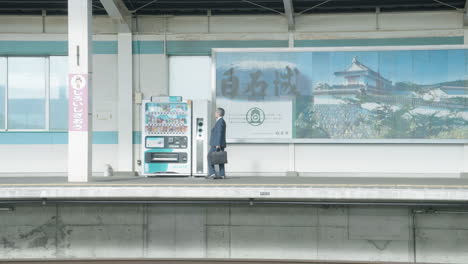 Japanese-Businessman-Walking-Towards-Vending-Machine-On-Platform-In-Sendai-Train-Station,-Japan