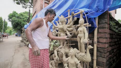 Poor-Asian-sculpture-making-idols-of-Hindu-goddess-Durga-with-clay,-slow-motion-track-zoom-in-shot