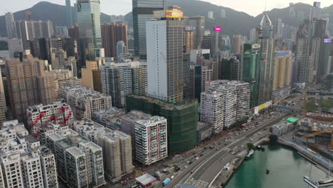 Aerial-View-of-Hong-Kong,-Wan-Chai-Central-District-Modern-Buildings-and-Traffic-at-Evening,-Revealing-Waterfront-Drone-Shot