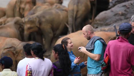Tourists-at-Pinnawala-Elephant-Orphanage-with-special-focus-on-a-white-couple-enjoying-and-taking-loved-up-photos-with-a-herd-of-elephants-in-the-background-in-Sabaragamuwa-Province-of-Sri-Lanka