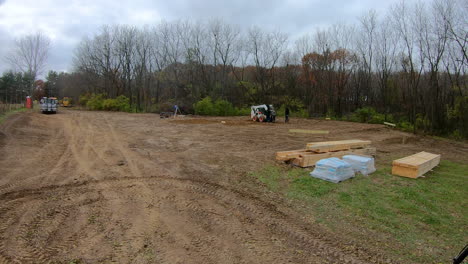 Small-construction-crew-using-a-skid-steer-loader-to-dig-holes-for-the-principal-framing-poles-for-new-construction-of-a-pole-barn