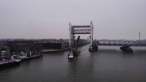 En-Avant-9-Tugboat-Pulling-Barge-With-Liebherr-Crane-Along-Oude-Maas-Through-Raised-Spoorbrug-Railway-Bridge