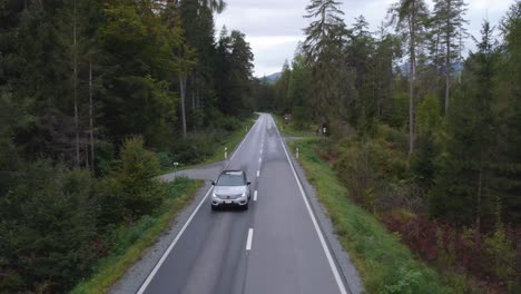 Aerial-view-in-front-a-Volvo-XC40-car-on-a-forest-road---pull-back,-drone-shot