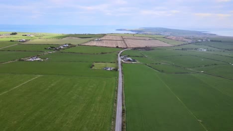 Straight-flight-backwards-over-countryside-road-near-Kinsale-with-the-view-over-green-fields-and-distant-clouds-over-ocean