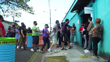 SAN-JOSÉ,-COSTA-RICA---FEBRUARY-6,-2022:-Election-Day-editorial,-a-queue-outside-the-voting-station,-with-people-standing-in-line,-slowly-moving-to-enter