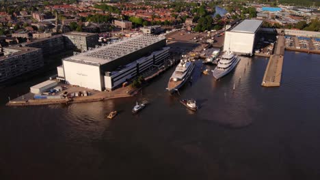 Aerial-View-Of-Tug-Boats-Helping-Luxury-Yacht-To-Dock-At-Oceanco-Shipyard-Marina