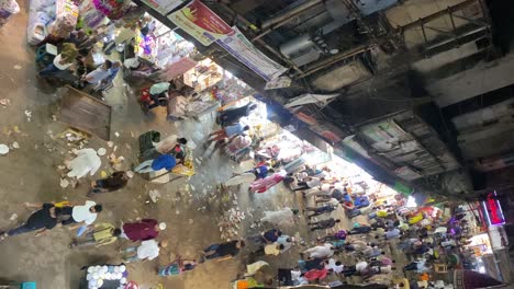 High-angle-shot-over-delicious-food-over-the-table-in-an-old-traditional-biggest-Iftar-food-market-in-Dhaka,-Bangladesh-with-rows-of-shops-at-nightime