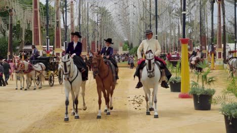 Three-people-riding-horses-at-the-Jerez-Fair-approach,-Spain